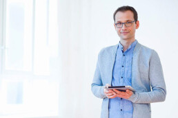Mann steht mit Tablet vor einem Fenster - modernes Businessbild
